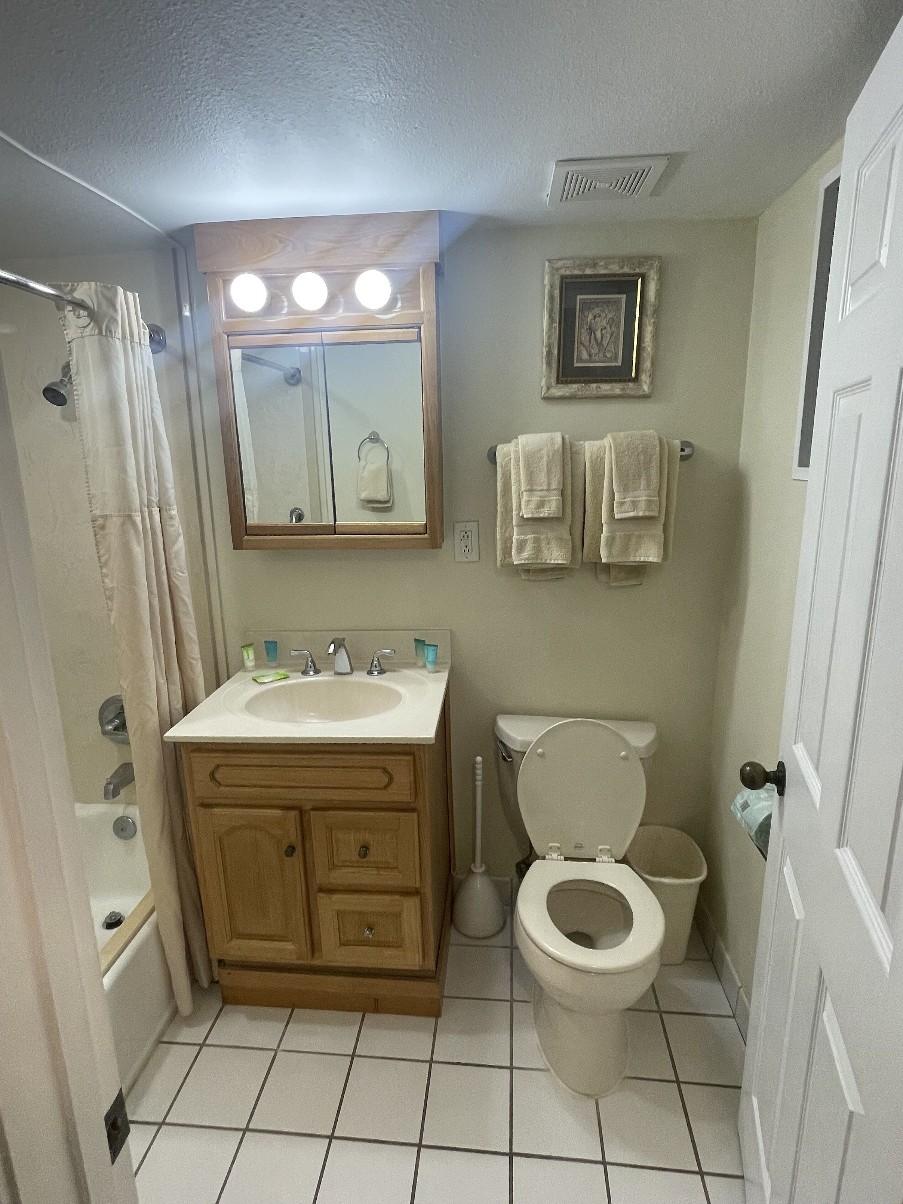 A bathroom with a sink, mirror, toilet, and shower.