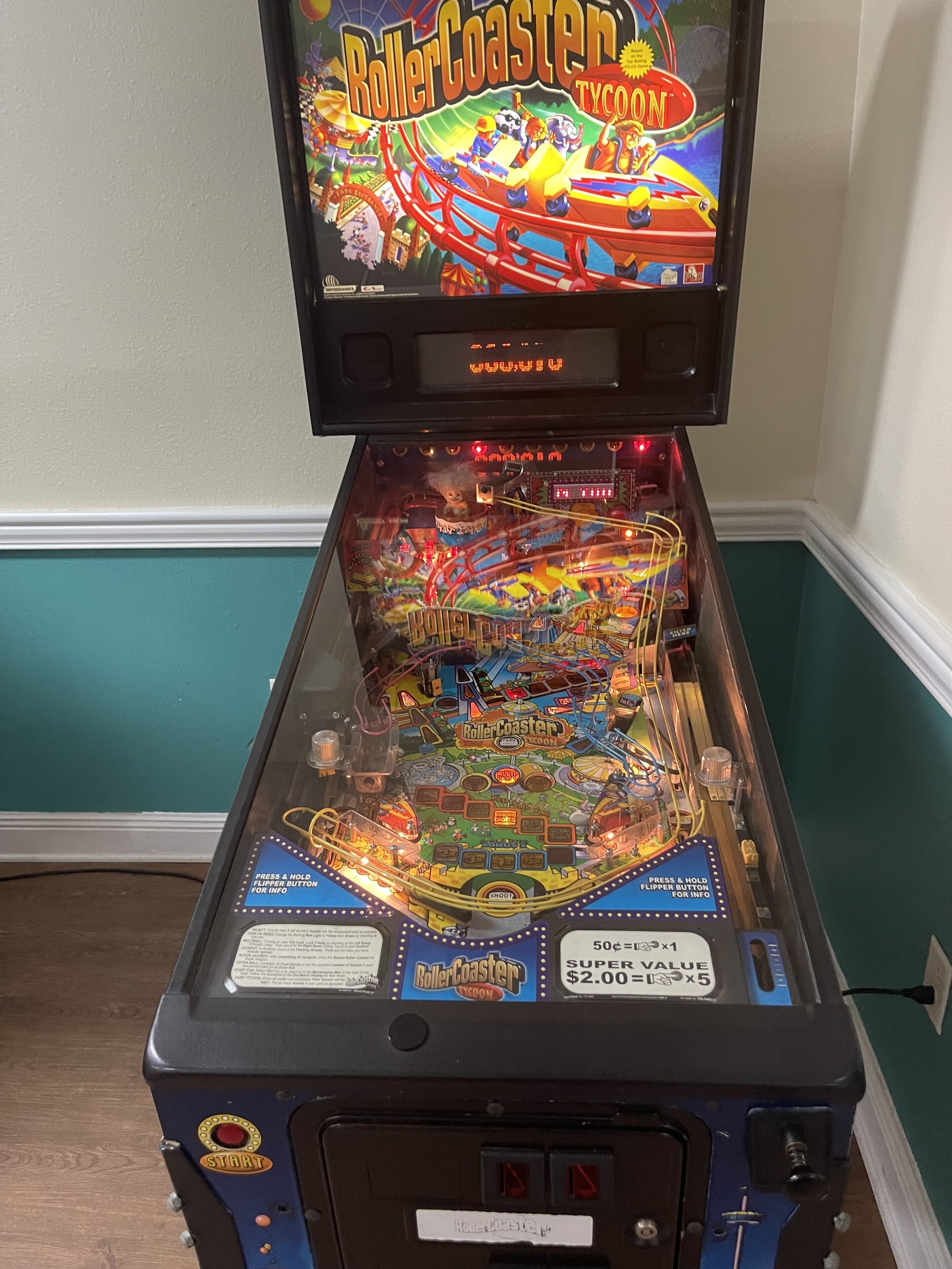 A pinball machine with a colorful design and a "RollerCoaster Tycoon" theme.