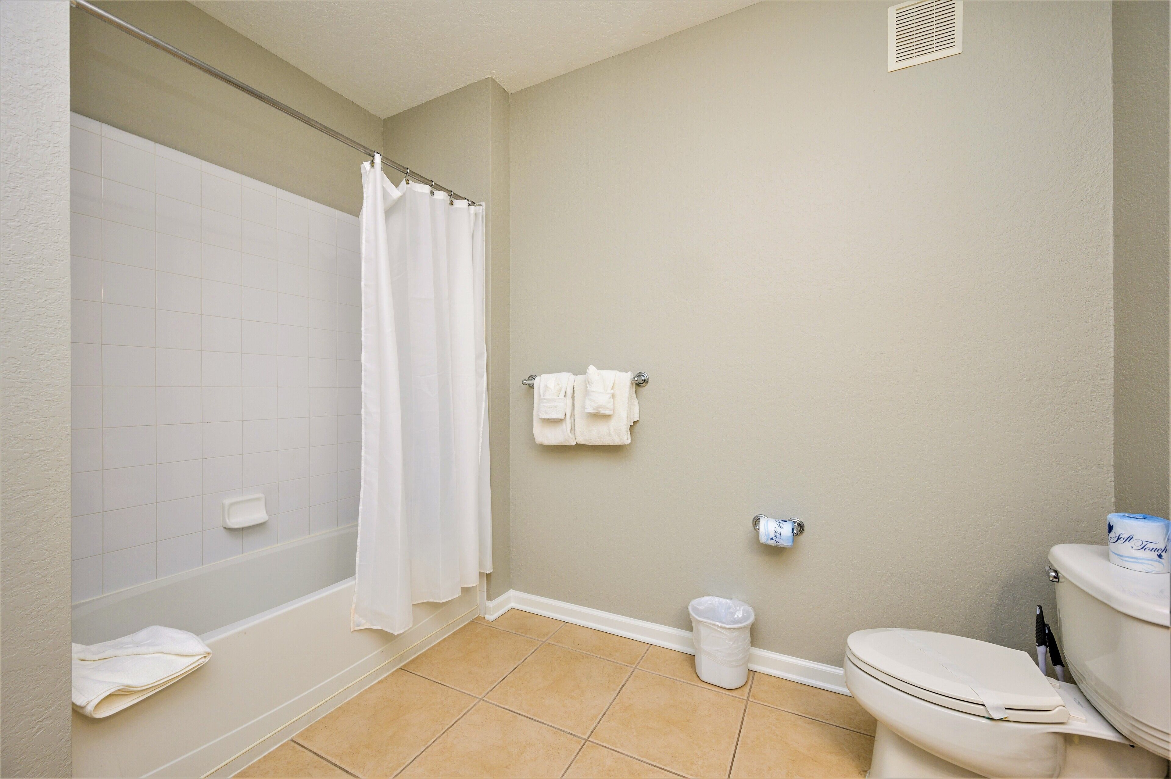 A bathroom with a bathtub, toilet, and a towel rack.
