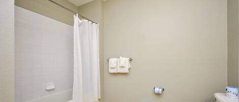 A bathroom with a bathtub, toilet, and a towel rack.
