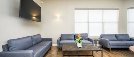 Un salon moderne avec deux canapés gris, une table basse en bois et une plante en pot.