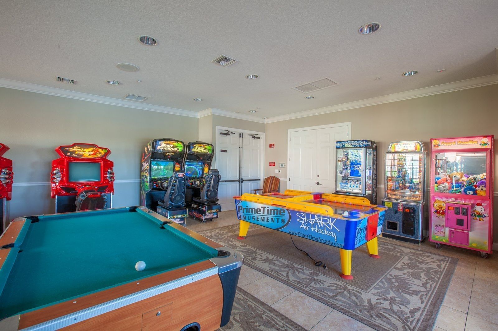 Una mesa de billar, juegos de arcade y una puerta en una habitación.