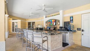 A bar area with a counter, bar stools, ceiling fans, and a tiled floor. - Vista Cay Resort by Millenium at Universal Blvd (Orlando)
