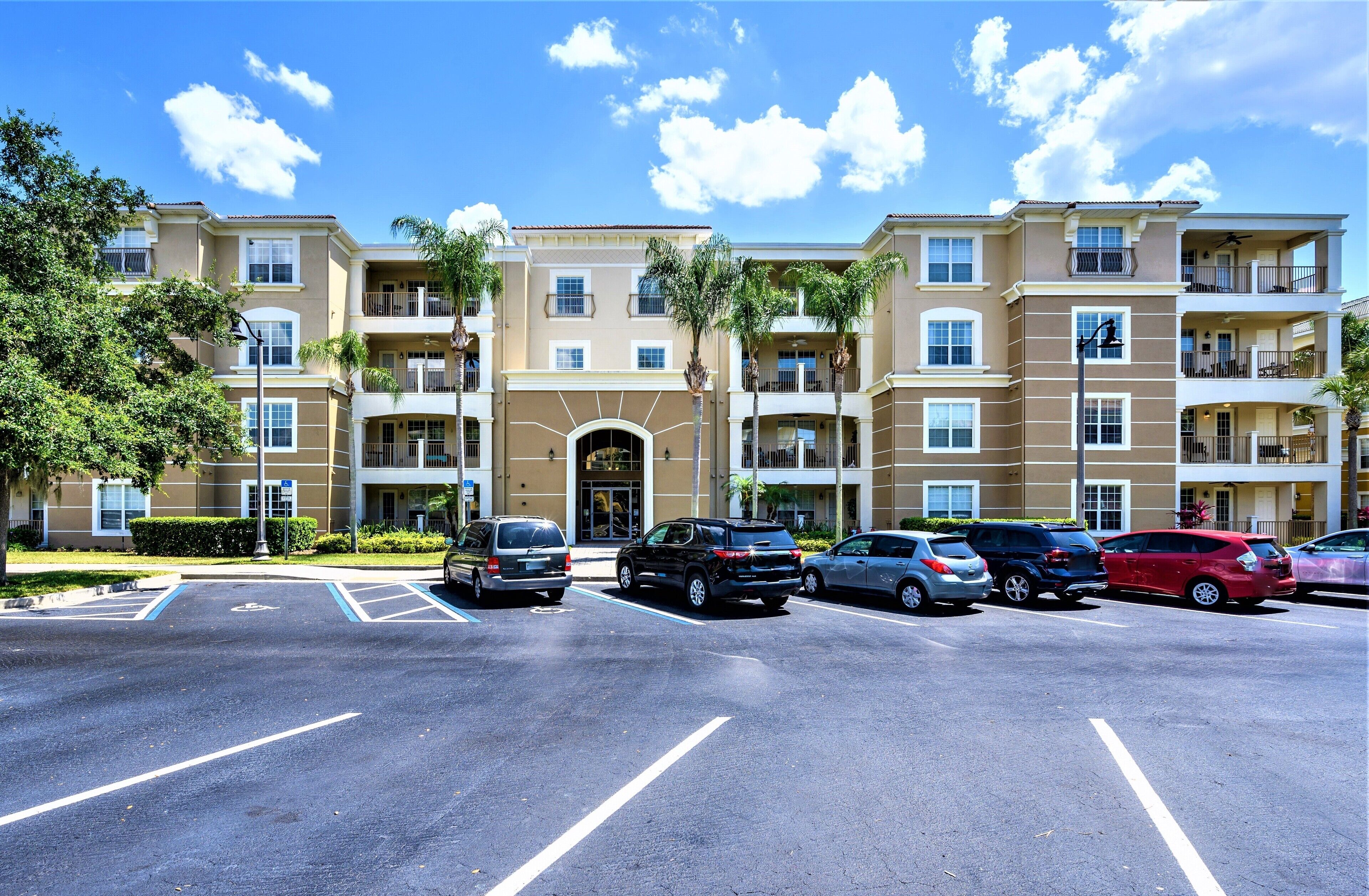 A multi-story apartment building with a parking lot in front.