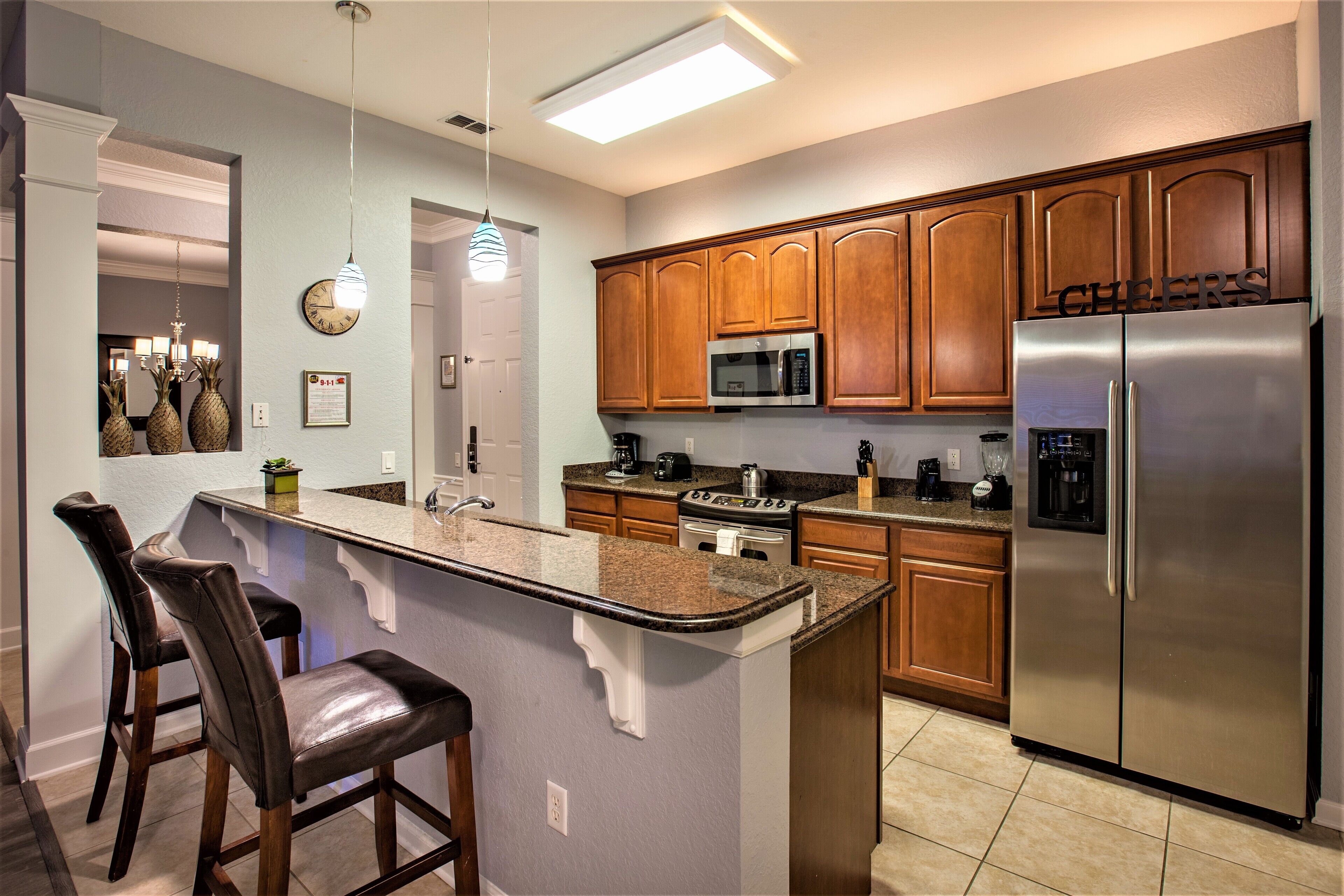 A modern kitchen with wooden cabinets, stainless steel appliances, and a central island with bar stools.