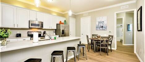 A modern kitchen with white cabinets, stainless steel appliances, and a central island with stools.