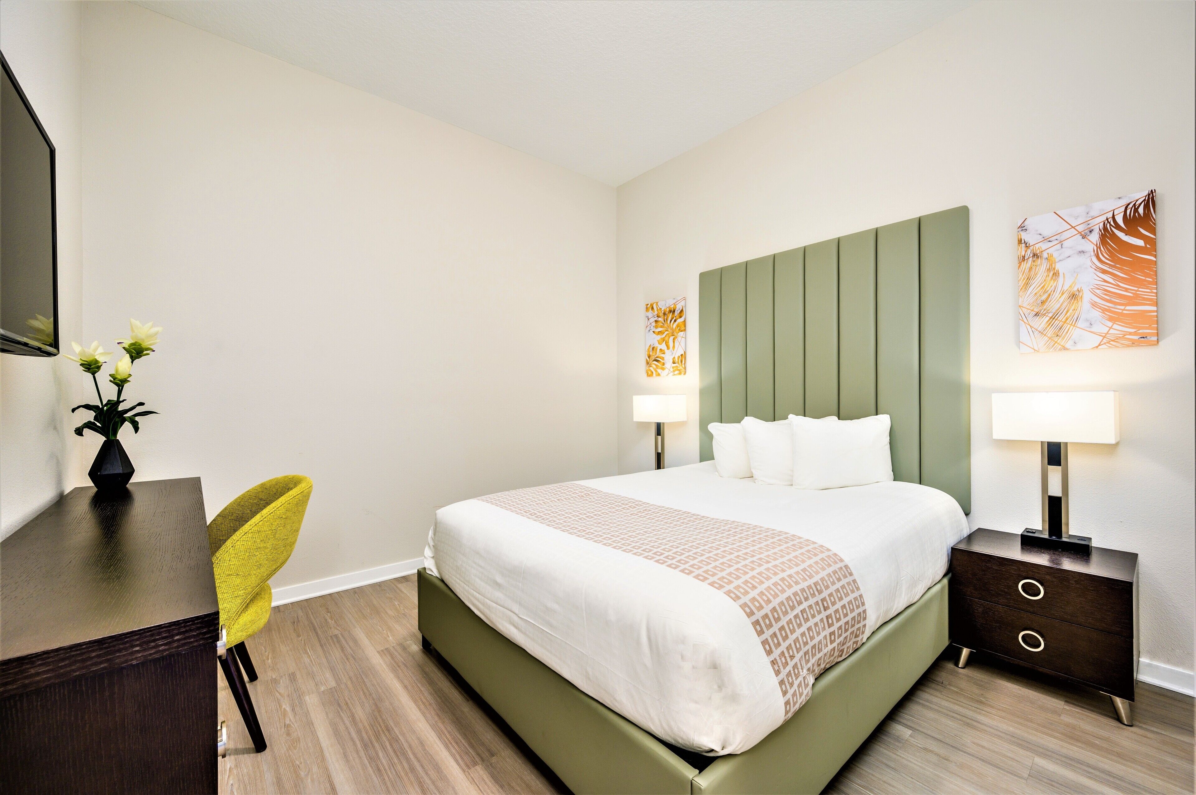 Una camera d'albergo con un letto, comodini, una scrivania, una sedia e uno specchio.