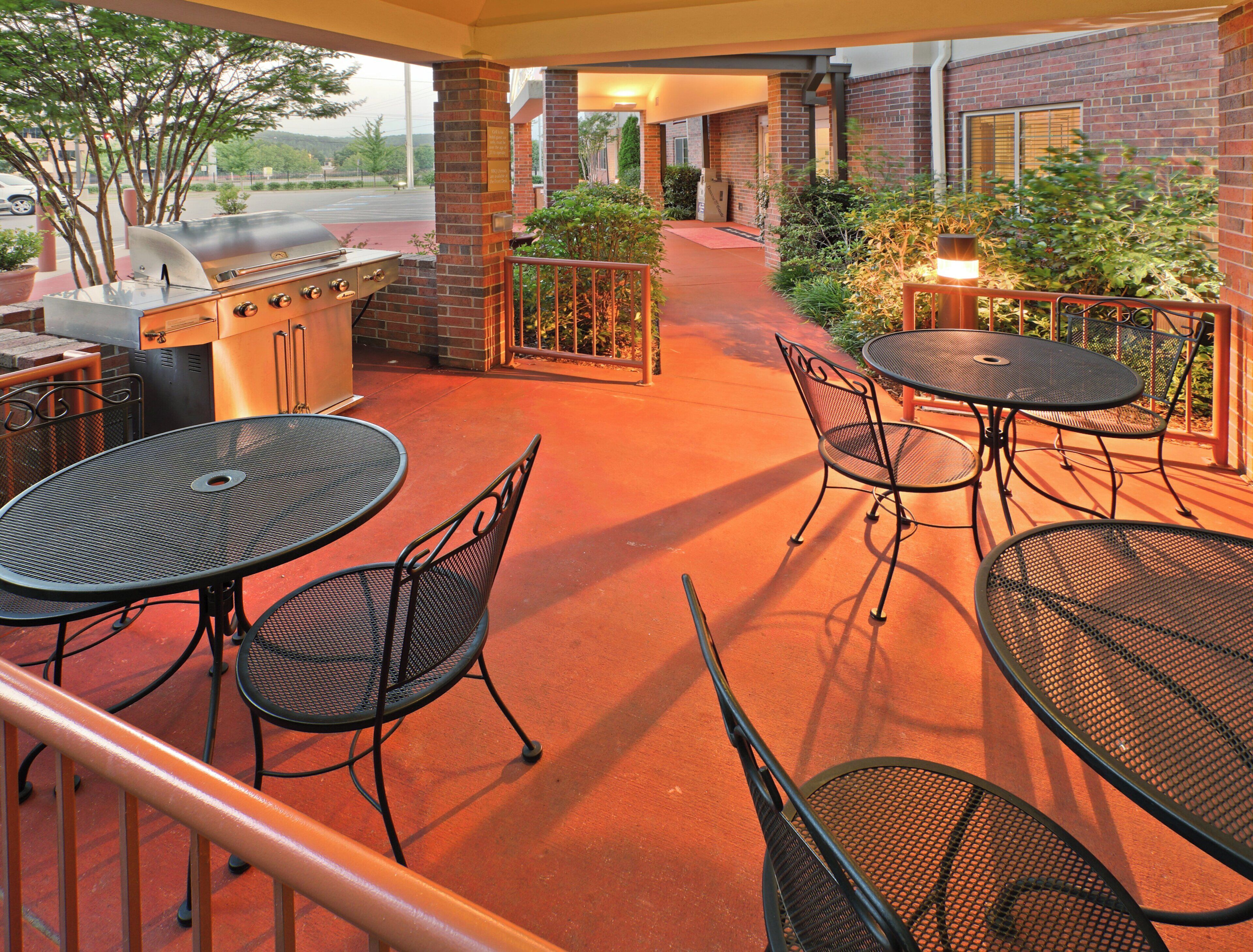 An outdoor patio with a grill, tables, and chairs.