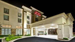 A Hampton Inn & Suites hotel with a stone facade, large windows, and a clear entrance.