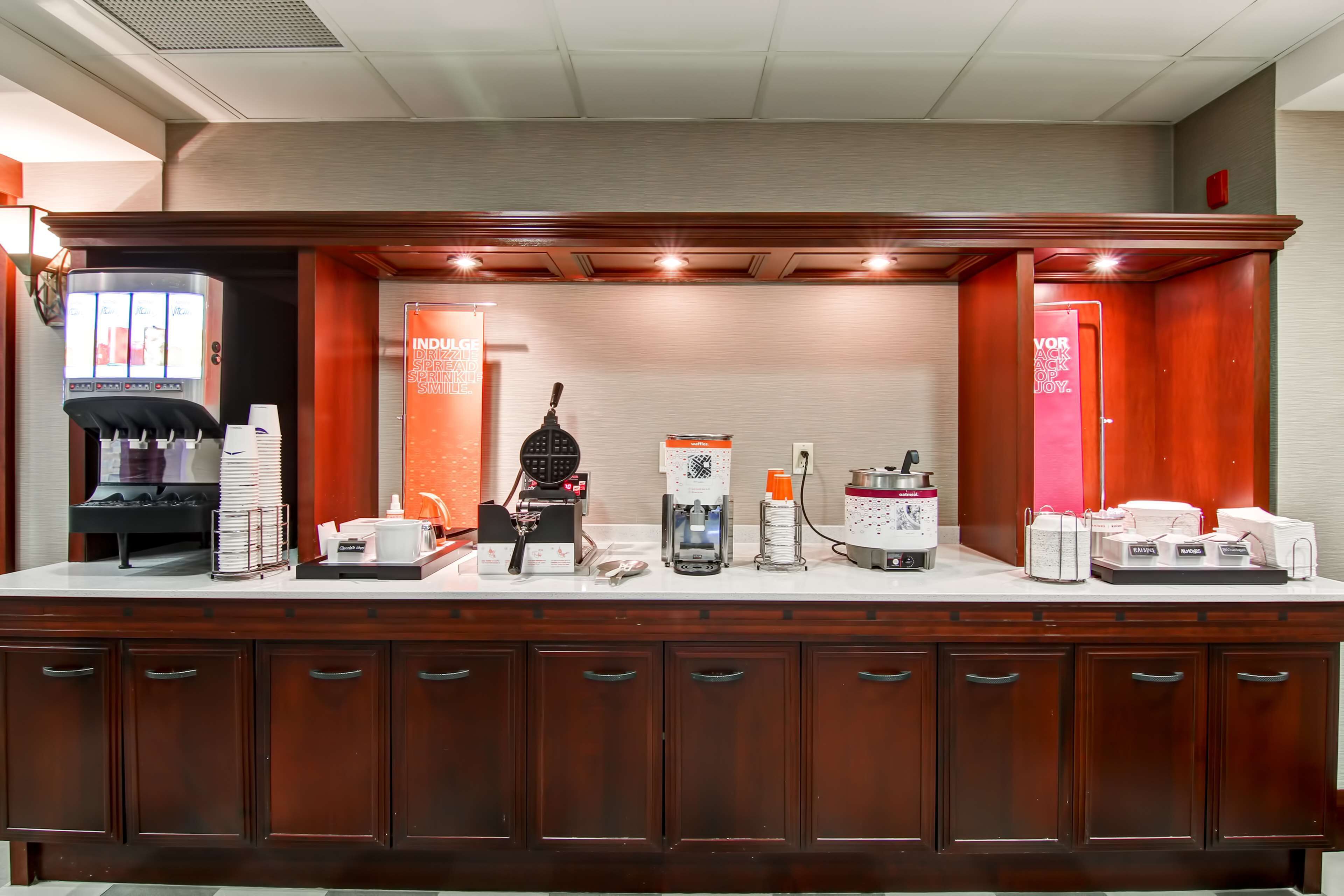 Uma área de recepção de hotel com uma máquina de café, uma balança e um saco para balança.