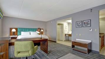 A hotel room with a bed, desk, chair, and a bathroom visible through an open door.