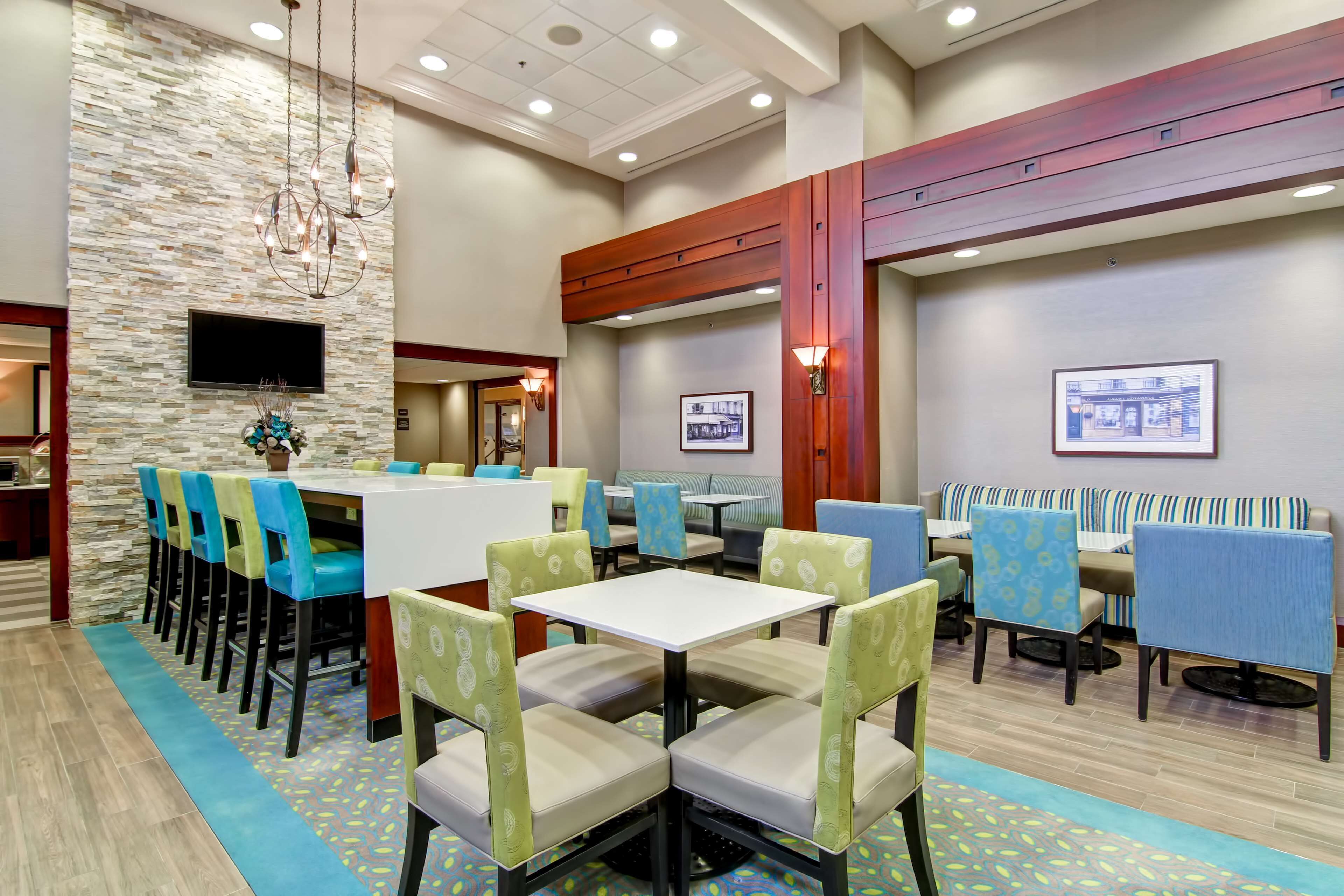 A hotel lobby with a stone wall, multiple seating areas, and a television screen.