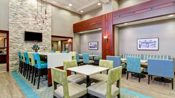 A hotel lobby with a stone wall, multiple seating areas, and a television screen.