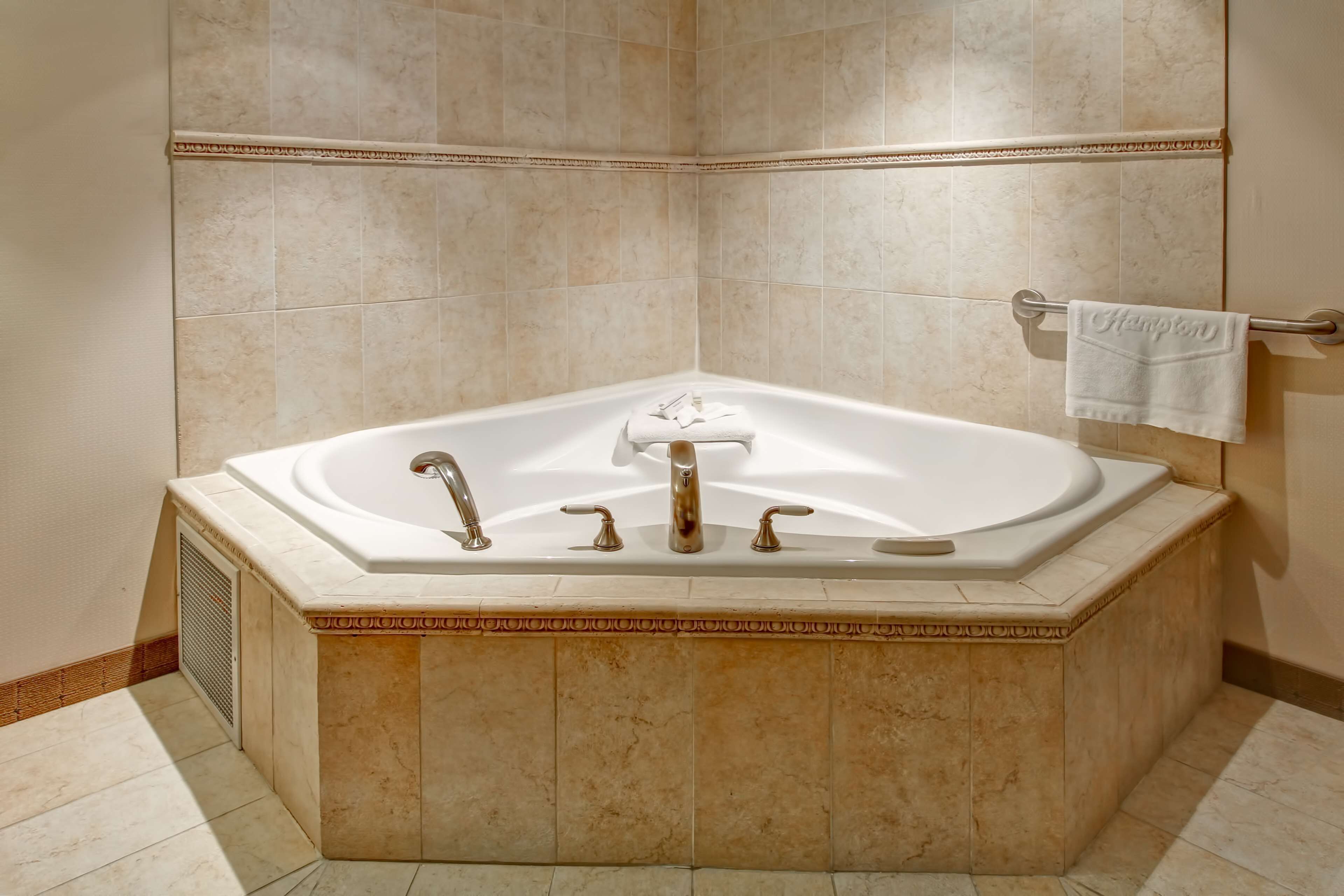 A large, freestanding bathtub with a towel rack above it.