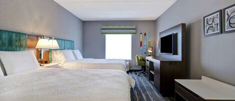 A hotel room with two beds, a desk, a TV, and a window with a view.