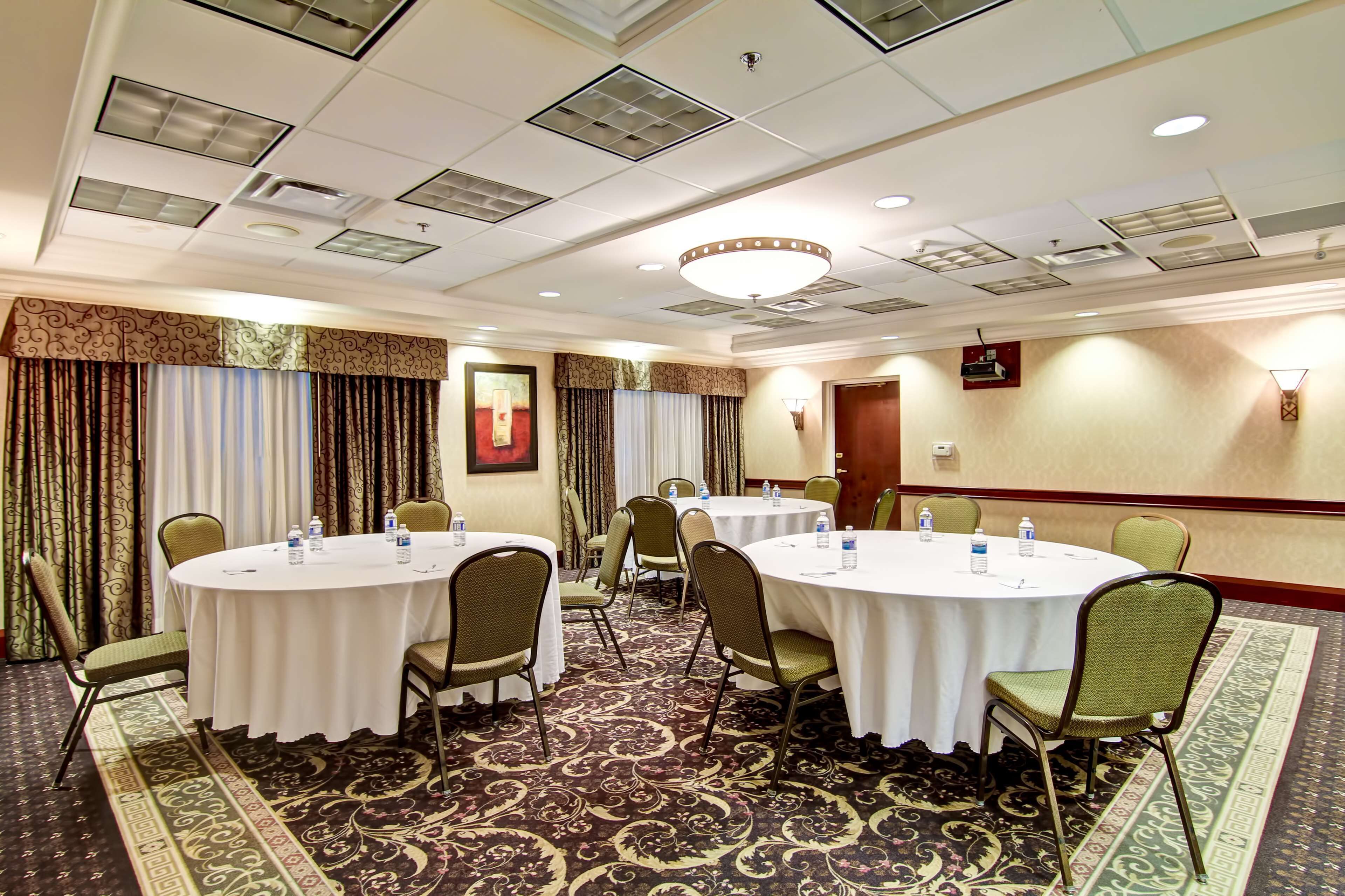Un salón de conferencias con mesas redondas, sillas y botellas de agua.