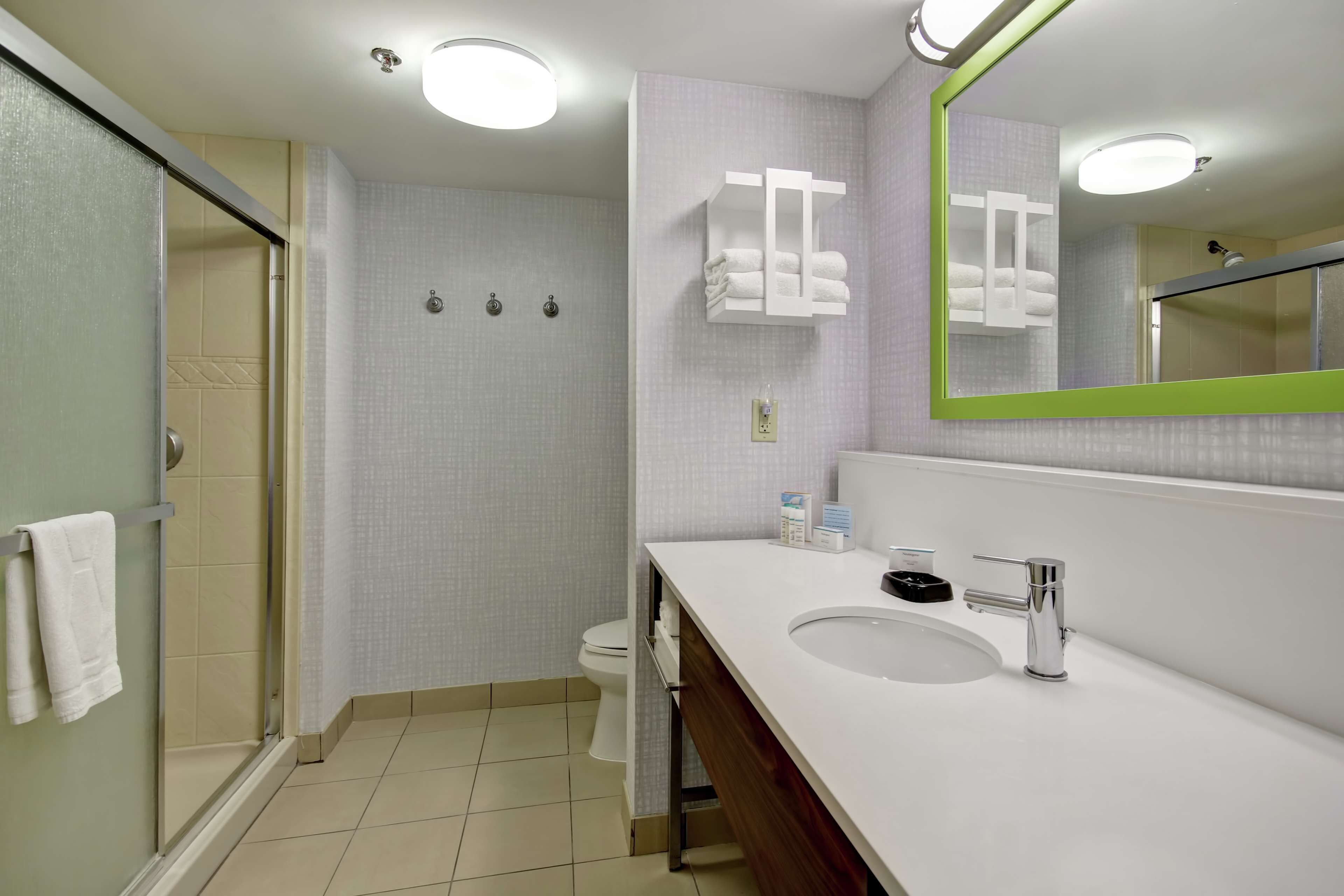 A modern bathroom with a glass shower enclosure, a white sink with a mirror, and a towel rack.