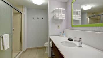 A modern bathroom with a glass shower enclosure, a white sink with a mirror, and a towel rack.