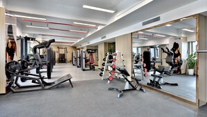 A gym with various exercise equipment, mirrors, and a clean, modern design. - Yindu Hotel Yiwu (Jinhua)