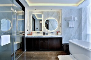 Un baño moderno con ducha de vidrio, tocador de mármol y bañera independiente.