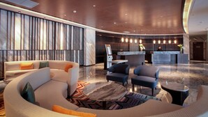 A spacious lobby with a curved sofa, a round marble table, and a reception desk. - Yindu Hotel Yiwu (Jinhua)
