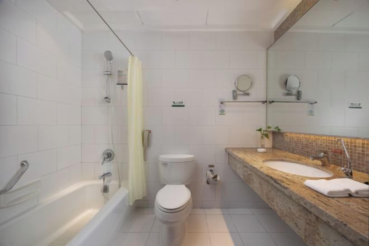 Un baño con bañera, inodoro y lavamanos con espejo.