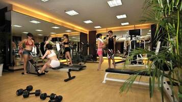 Un gimnasio con equipo de ejercicio, espejos y piso de madera.