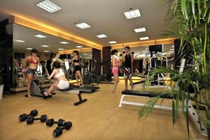 Ein Fitnessstudio mit Trainingsgeräten, Spiegeln und Holzboden.