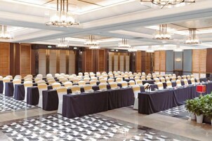 Un salón de conferencias con filas de mesas, sillas y una zona de escenario.