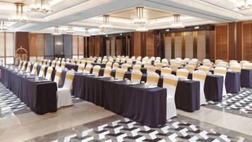 A conference room with rows of tables, chairs, and a stage area.