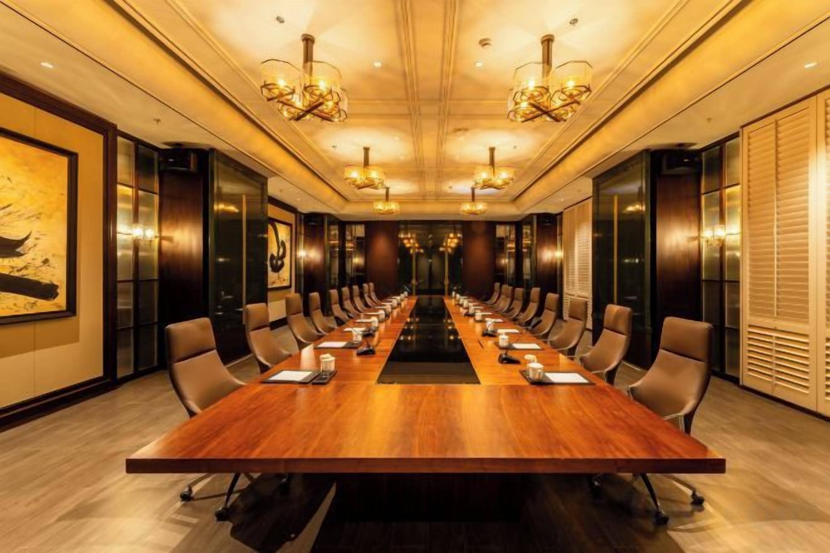 Un salón de conferencias con una larga mesa, sillas y candelabros.