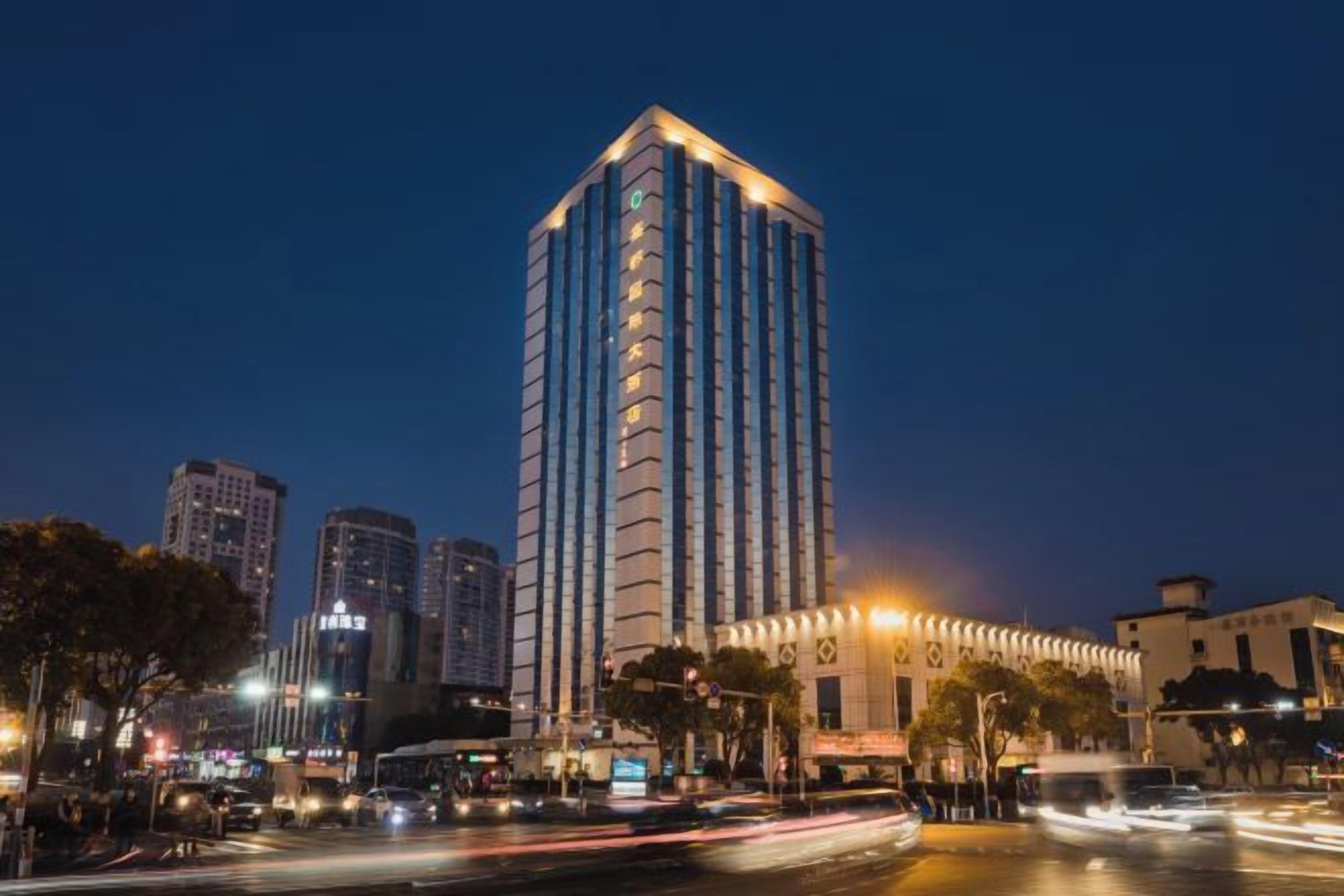 A high-rise building with a modern design, located in an urban setting with other buildings and a busy street.