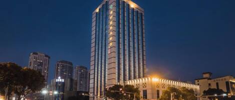 A high-rise building with a modern design, located in an urban setting with other buildings and a busy street.