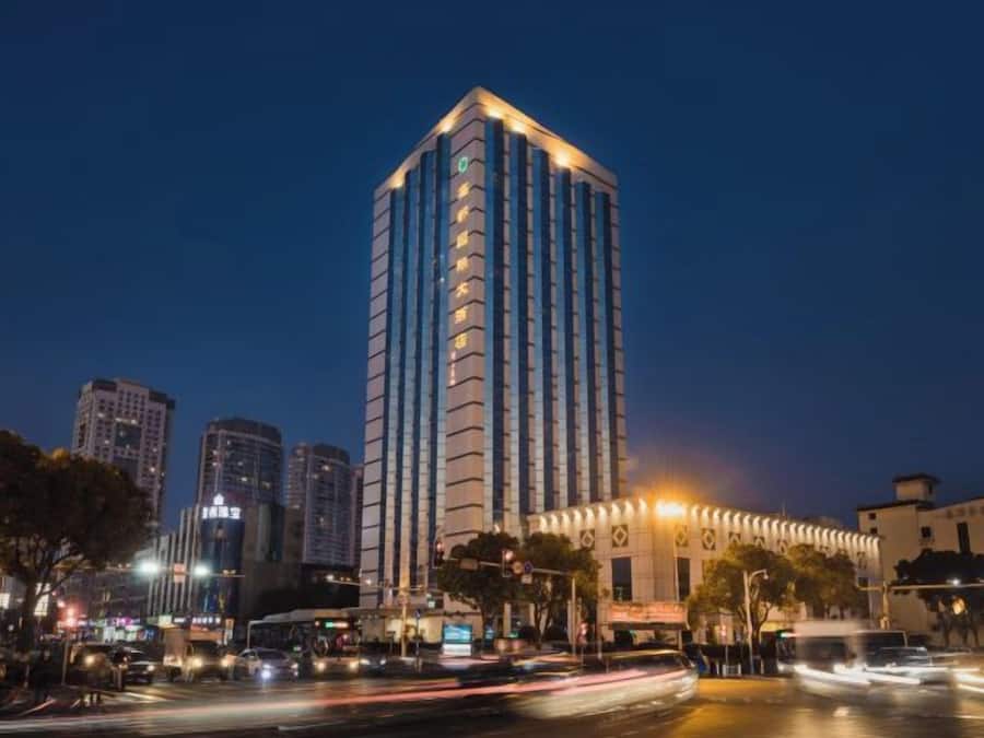 A high-rise building with a modern design, located in an urban setting with other buildings and a busy street.