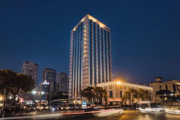 A high-rise building with a modern design, located in an urban setting with other buildings and a busy street. - XINDU INTERNATIONAL HOTEL (Taizhou)