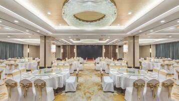 A banquet hall with round tables, white tablecloths, and gold sashes.