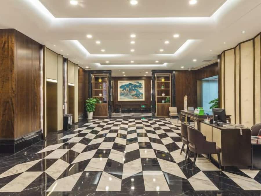 A hotel lobby with a checkered floor, reception desk, and a large painting on the wall.