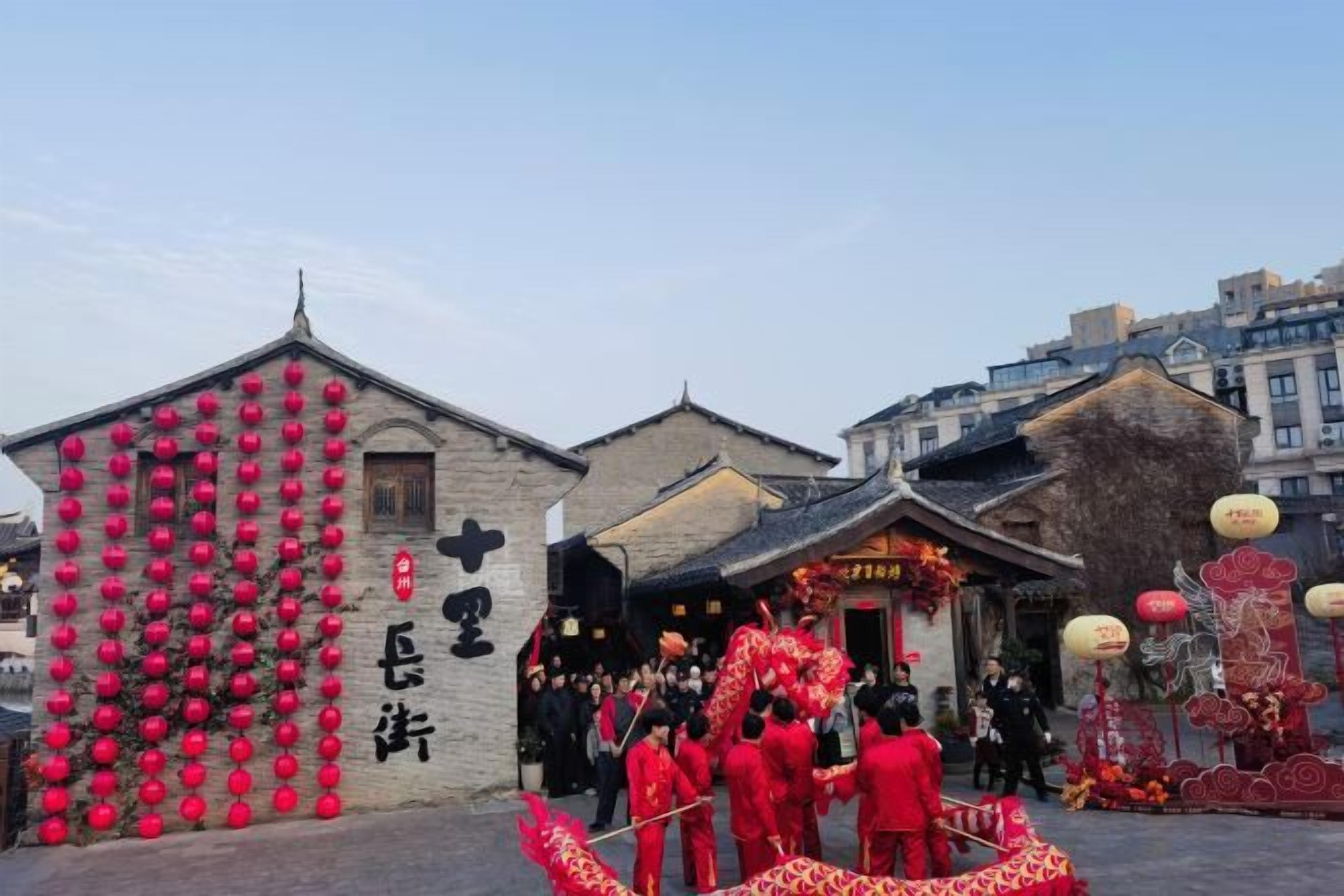 Un bâtiment traditionnel avec une enseigne, un groupe de personnes vêtues de rouge et une figurine de dragon décorative.