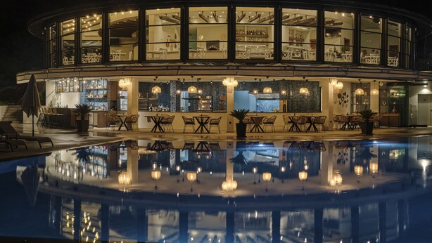 A hotel with a pool, outdoor seating, and a bar area.