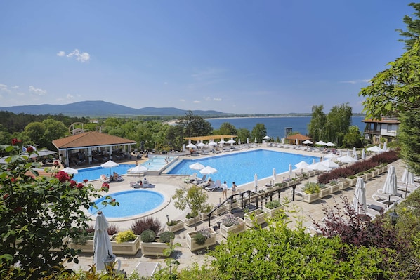 Un resort con una amplia piscina, sillas de descanso y vistas al lago.