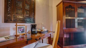 A wooden desk with a coffee maker, a framed picture, and a chair.