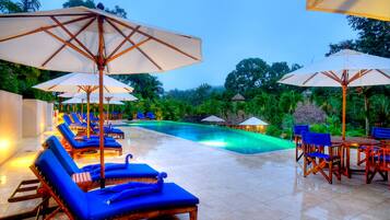 Alberca al aire libre, sombrillas en la alberca y camastros