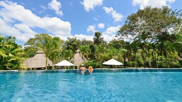 Una piscina al aire libre, sombrillas, sillones reclinables de piscina