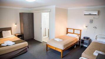 Une chambre d’hôtel avec deux lits, une armoire, une table de chevet, un appareil de climatisation et une chaise.