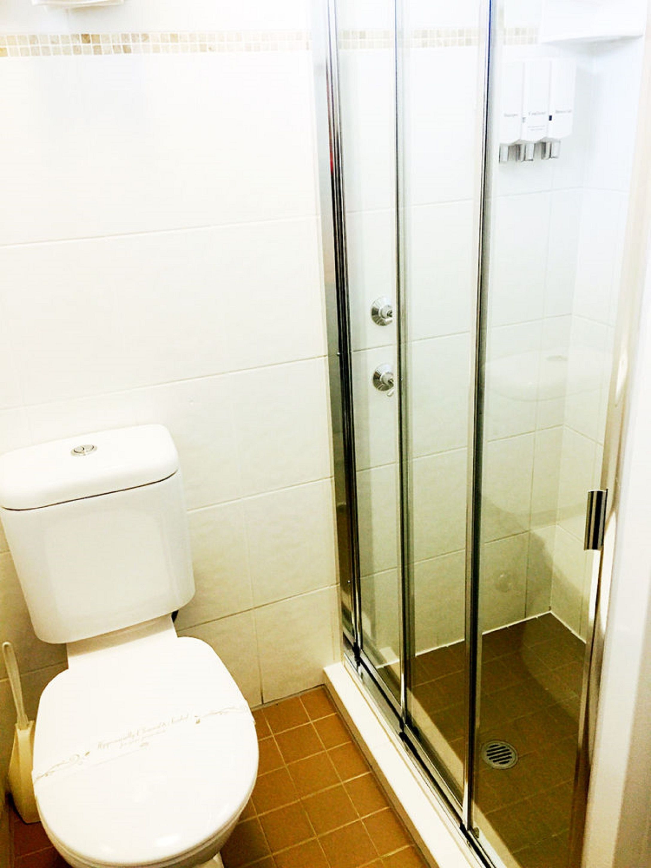 Ein Badezimmer mit Toilette, Duschkabine aus Glas und Fliesenboden.