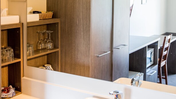 Un bagno moderno con uno specchio grande, un lavandino bianco e un armadio in legno.
