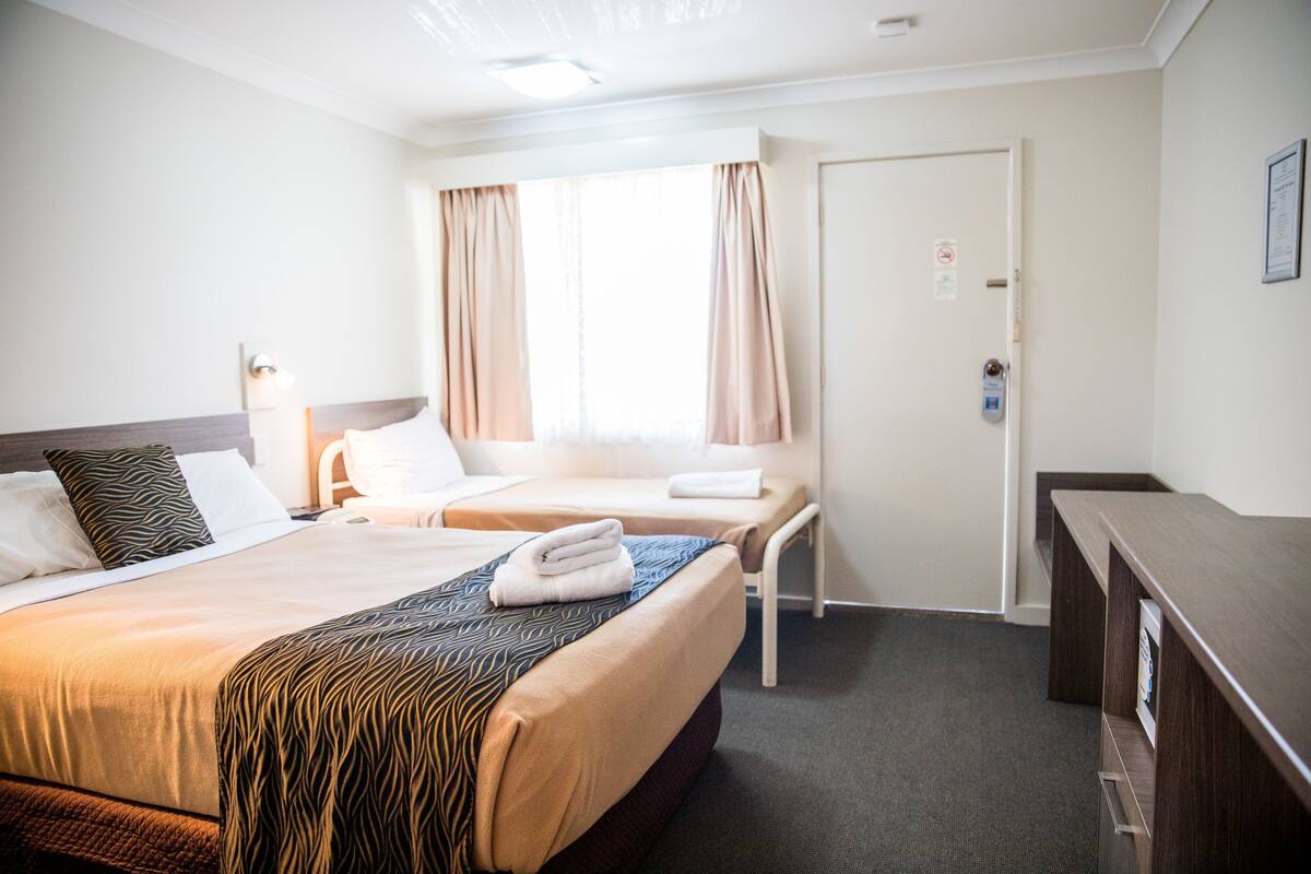 Una habitación de hotel con dos camas, un escritorio y una puerta.