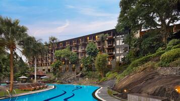 Un hotel con piscina, varios balcones y abundante vegetación.