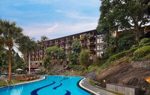 Un hotel con piscina, varios balcones y abundante vegetación.
