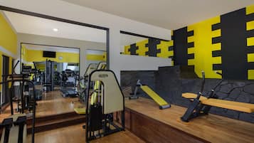 A gym with exercise equipment, a mirror, and a yellow and black wall design.